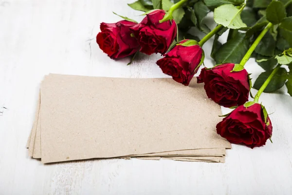 Rode roos en papier voor gefeliciteerd met een houten achtergrond. — Stockfoto