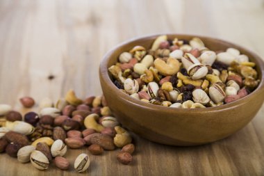 Ahşap bir masa üzerinde bir ahşap kase fındık. 