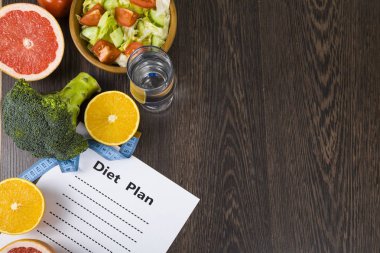 Gıda ve koyu ahşap bir masa üzerinde bir diyet planı ile kağıt.