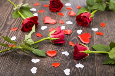 Kırmızı gül ve kalpleri bir ahşap zemin üzerine. 