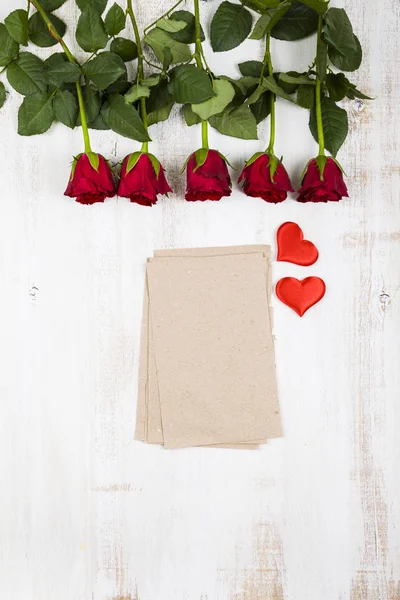 Κόκκινα τριαντάφυλλα και κάρτα σε σκούρο φόντο ξύλινη. — Φωτογραφία Αρχείου