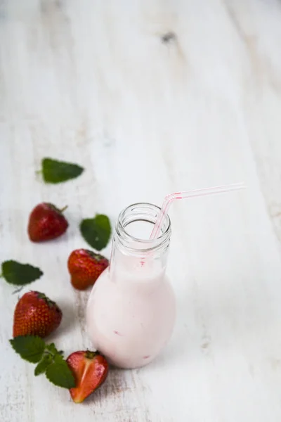 Smoothies e morango maduro em uma mesa de madeira . — Fotografia de Stock