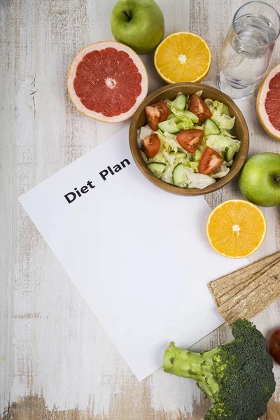 Food and sheet of paper with a diet plan on a dark wooden table. — Stock Photo, Image