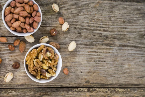 Nueces en un plato sobre una mesa de madera . — Foto de Stock