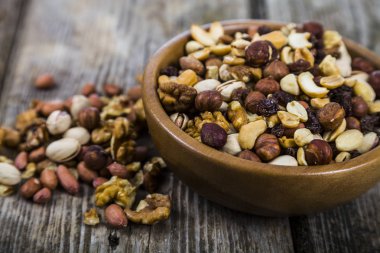 Ahşap bir masa üzerinde bir ahşap kase fındık. 