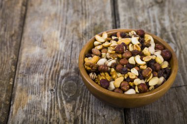 Ahşap bir masa üzerinde bir ahşap kase fındık. 