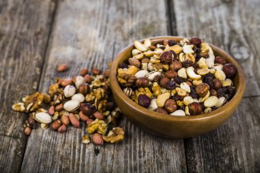 Ahşap bir masa üzerinde bir ahşap kase fındık. 