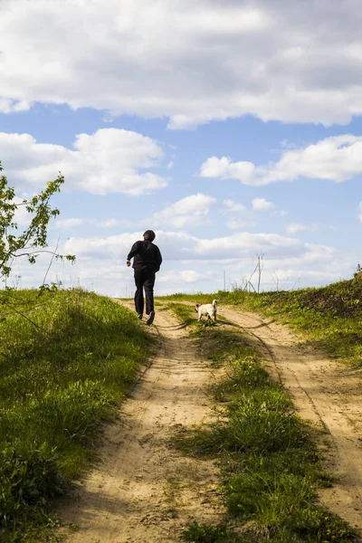 牧草地に道路を歩く犬とティーンエイ ジャー. — ストック写真
