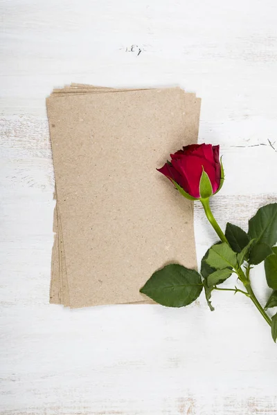 Червона троянда і папір для привітань на дерев'яному фоні — стокове фото