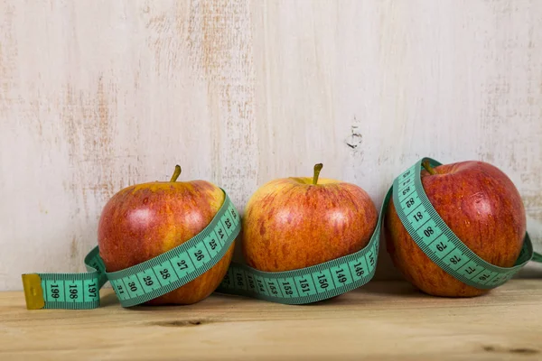 Tres manzanas y cinta métrica en una mesa de madera. Concepto de di —  Fotos de Stock
