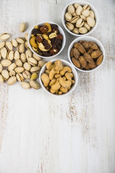 Cuatro cuencos con nueces en una mesa de madera — Foto de Stock