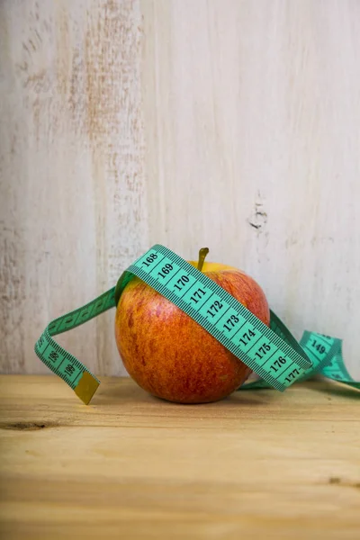 Manzana y cinta métrica en una mesa de madera . —  Fotos de Stock