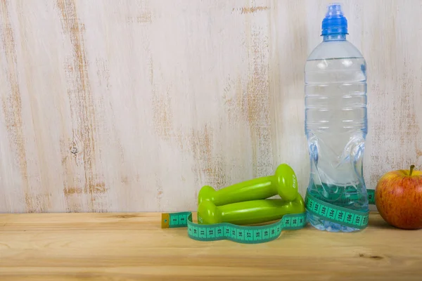 Manubri e una bottiglia d'acqua su un tavolo di legno — Foto Stock