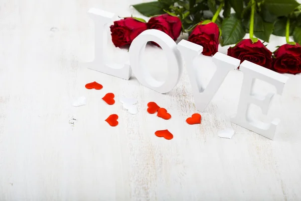 Röda rosor och ordet ”kärlek" — Stockfoto