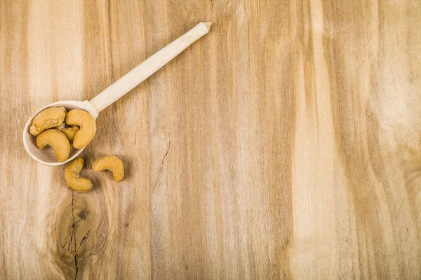 Cashew in a spoon on a wooden table — Stock Photo, Image