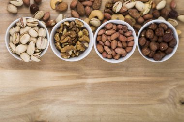 Ahşap bir masa üzerinde fındık ile dört kase. 