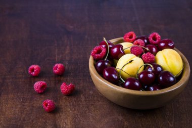 Ahşap bir masa üzerinde bir tabak içinde olgun çilek.  