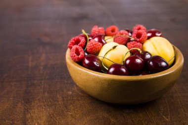 Ahşap bir masa üzerinde bir tabak içinde olgun çilek.  