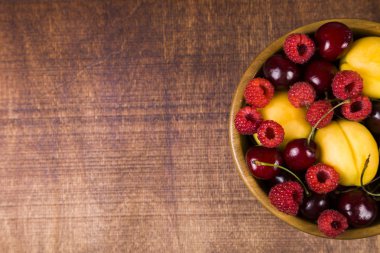 Ahşap bir masa üzerinde bir tabak içinde olgun çilek.  