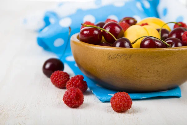 Ahşap bir masa üzerinde bir tabak içinde olgun çilek.  