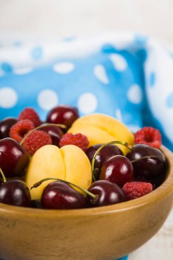 Ahşap bir masa üzerinde bir tabak içinde olgun çilek.