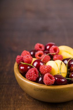 Ahşap bir masa üzerinde bir tabak içinde olgun çilek. 