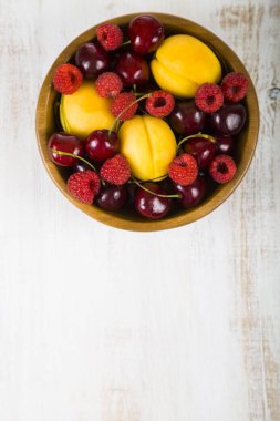 Ahşap bir masa üzerinde bir tabak içinde olgun çilek. 