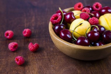 Ahşap bir masa üzerinde bir tabak içinde olgun çilek.  