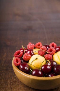 Ahşap bir masa üzerinde bir tabak içinde olgun çilek.  