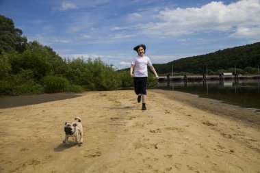 Çocuk ve kumlu bir plaj çalışan köpek