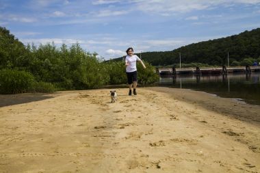 Çocuk ve kumlu bir plaj çalışan köpek