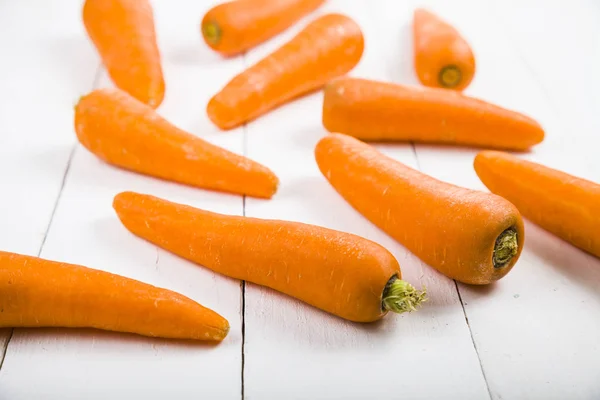 Rijpe wortelen op een witte tafel — Stockfoto