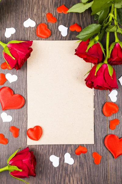 Red roses and card on a wooden background. — Stock Photo, Image