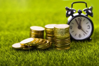 Çalar saat ve sikkeler çimenlerin üzerinde.