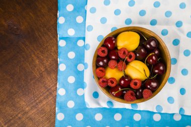 Ahşap bir masa üzerinde bir tabak içinde olgun çilek.