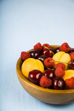 Ahşap bir masa üzerinde bir tabak içinde olgun çilek.