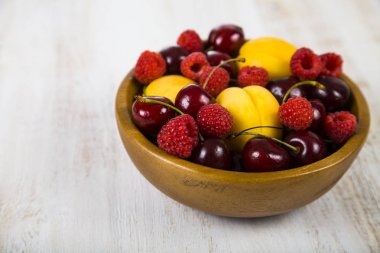 Ahşap bir masa üzerinde bir tabak içinde olgun çilek.