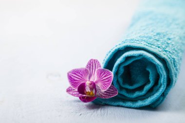 Beyaz ve mavi havlu ve bir orkide çiçeği.