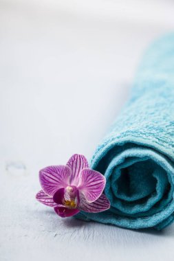 Beyaz ve mavi havlu ve bir orkide çiçeği.