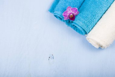 Beyaz ve mavi havlu ve bir orkide çiçeği.