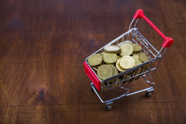 Carrello della spesa con monete su un tavolo di legno . — Foto Stock