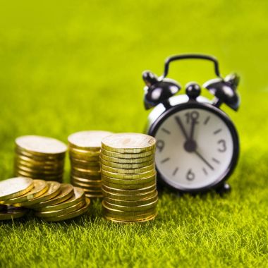 Çalar saat ve sikkeler çimenlerin üzerinde.