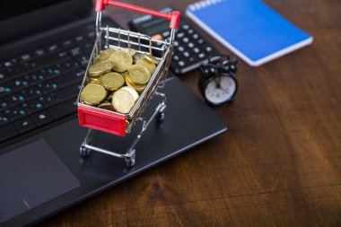 Paralar, dizüstü bilgisayar ve çalar saat ile alışveriş arabası