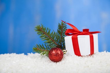 Kar üzerinde kırmızı fiyonklu hediye paketi  