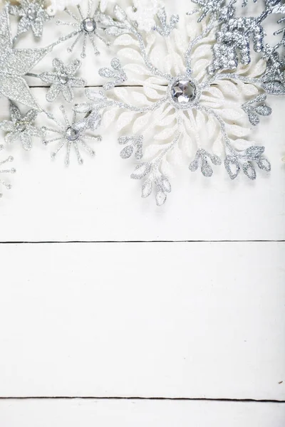 Silbrige Schneeflocken auf weißem Holzgrund. — Stockfoto