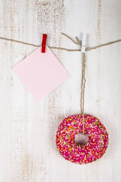 Pink donut and a piece of paper on a rope — Stock Photo, Image