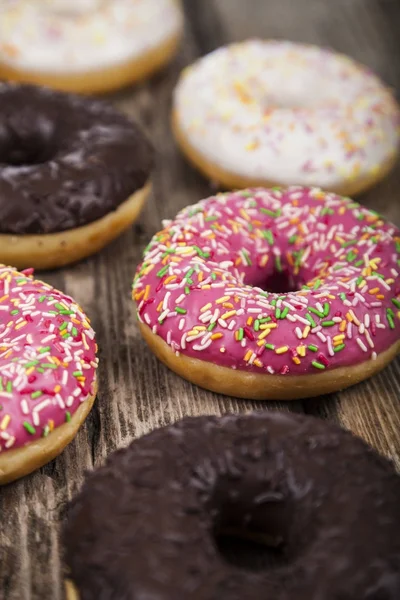 Multicolored donuts  on a wooden background. — Stock Photo, Image