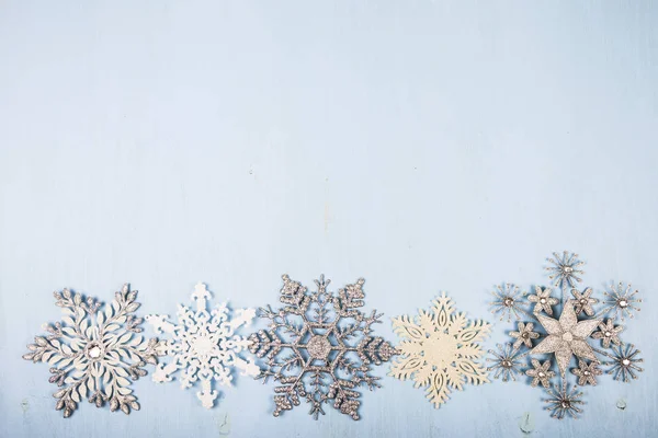 Flocos de neve prateados em um fundo de madeira . — Fotografia de Stock