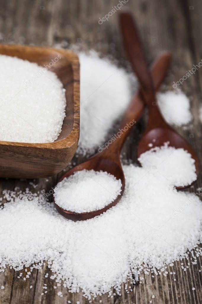 Sugar in a wooden bowl and  two spoons 