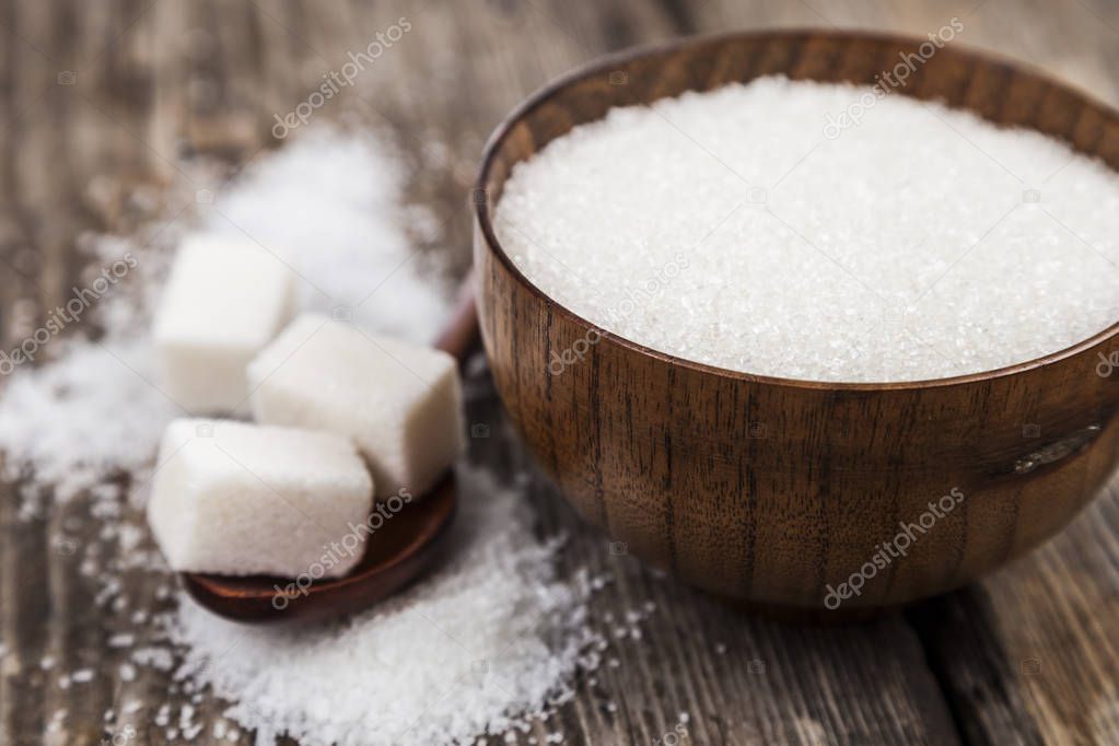 Sugar in a wooden bowl and a spoon  